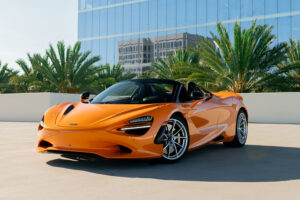 Orange McLaren 750S from Monza Exotics parked on a rooftop in front of a glass office tower
